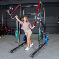 Thumbnail for Woman using a black and red jammer strength trainer with weight plates in a gym.