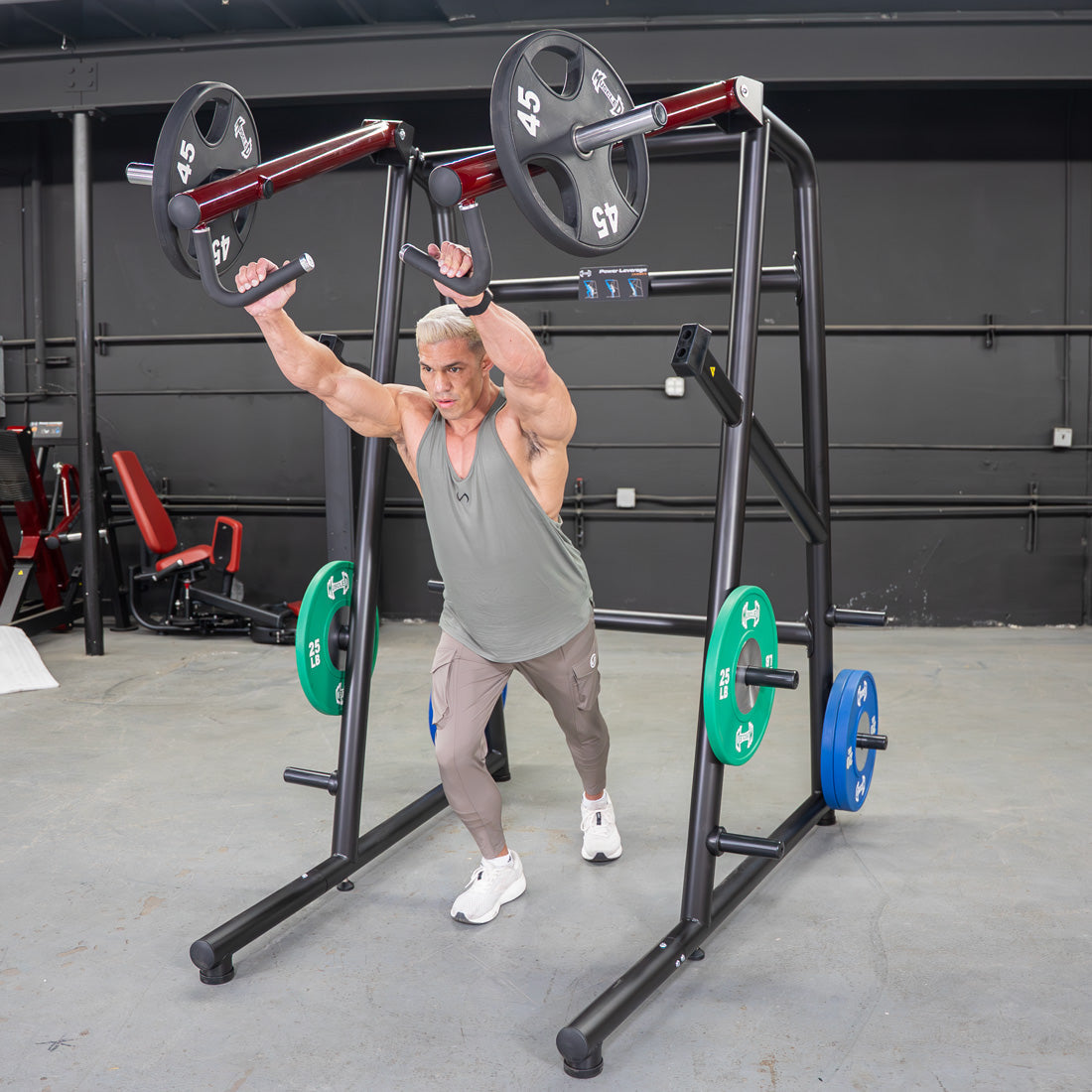 Man in a gym using a black Power Leverage V2 Jammer with weight plates on the arms and storage pegs.