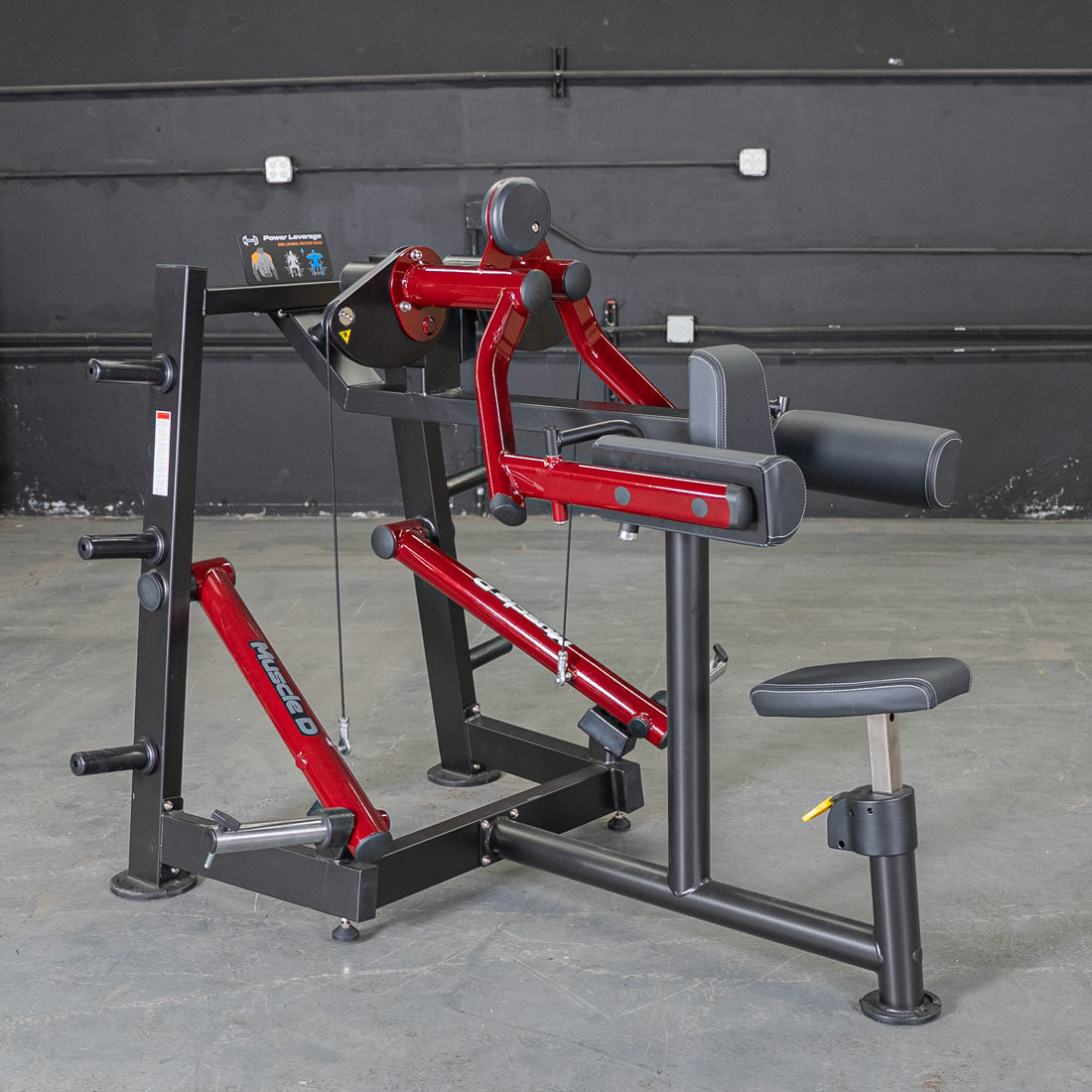 Red and black lateral raise machine with padded armrests and seat.