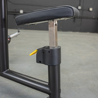 Thumbnail for Close-up of a black padded seat with white stitching, adjustable height mechanism, and yellow lever on a fitness machine.