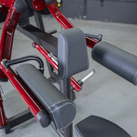 Thumbnail for Close-up of a red and black lateral raise machine with padded armrests and back support.