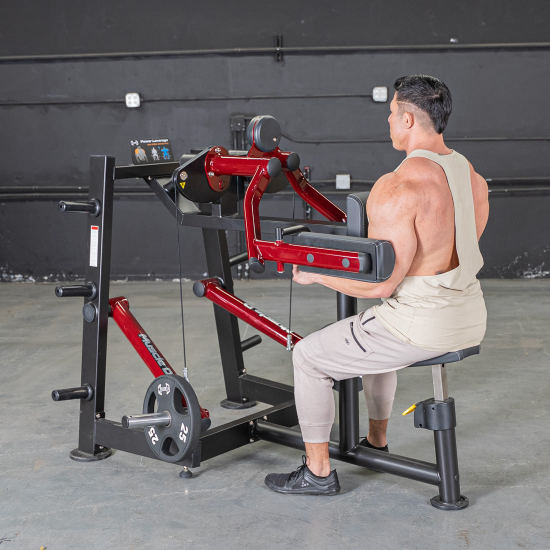 Man using a red and black lateral raise machine in a gym.