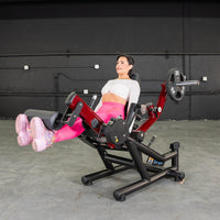 Thumbnail for Woman performing leg extensions on a red and black seated leg extension/prone leg curl machine.