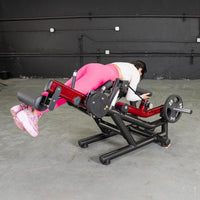 Thumbnail for Woman in pink leggings using a red and black leg extension/curl machine with a 25lb weight plate.