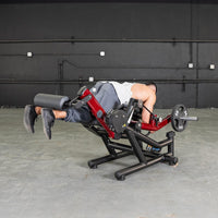 Thumbnail for Man doing prone leg curls on a red and black combo machine with a 25lb weight plate.