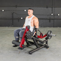 Thumbnail for Man seated on a red and black leg extension/curl machine with a 25lb weight plate.