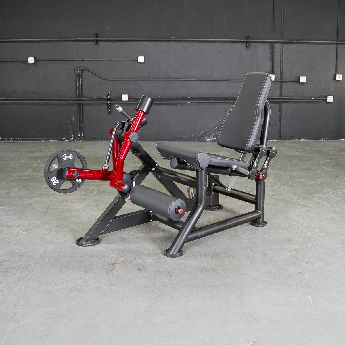 Red and black leg extension machine with a 25lb weight plate on a concrete floor.