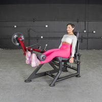 Thumbnail for Woman in pink leggings using a red and black leg extension machine with a 25lb weight plate.