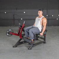 Thumbnail for Man seated on a red and black leg extension machine with a 25lb weight plate.