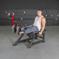 Thumbnail for Man using a red and black leg extension machine with a 25lb weight plate in a gym.
