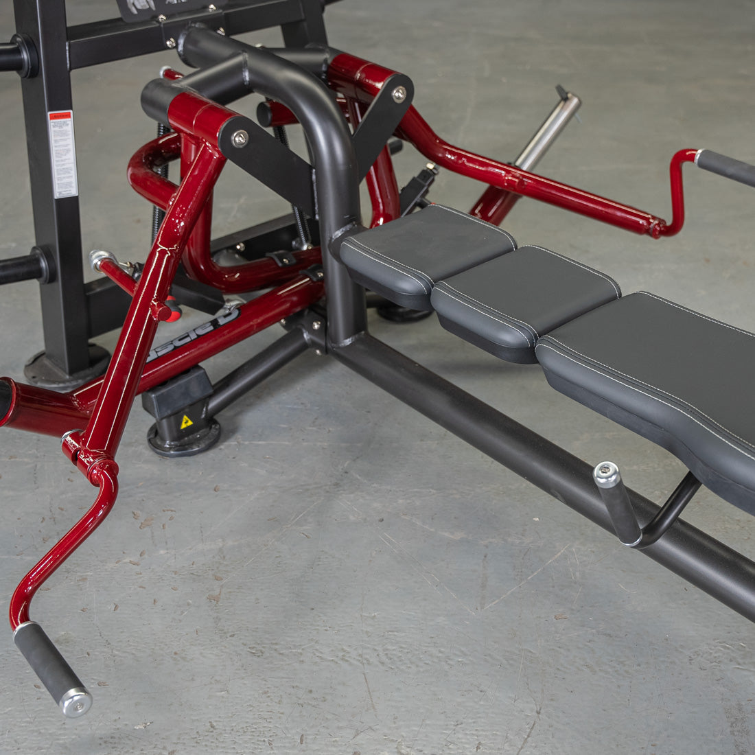 Red and black lying pec fly machine with an adjustable bench and padded handles.