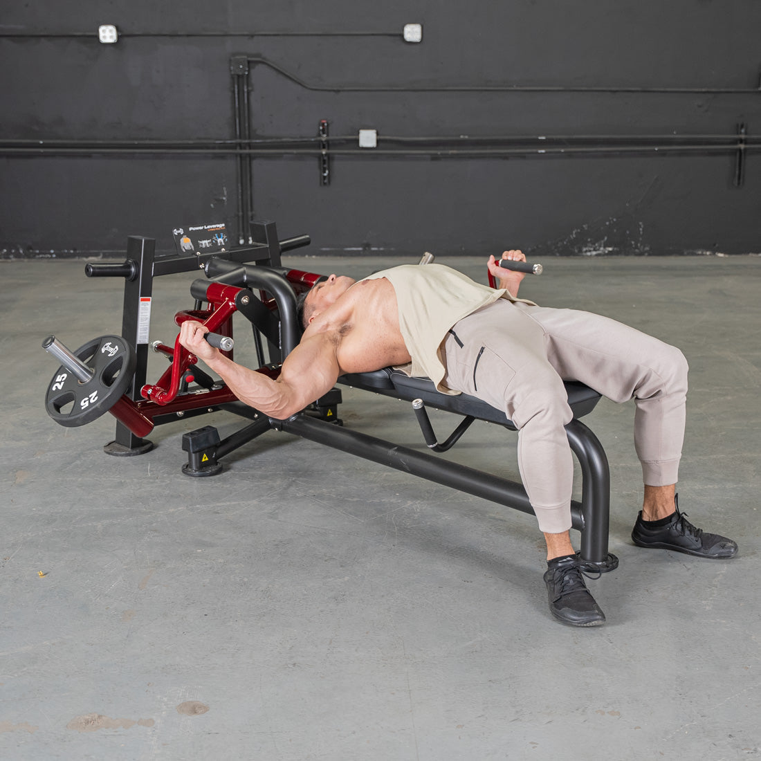 Man using a lying pec fly machine with weight plates in a gym.