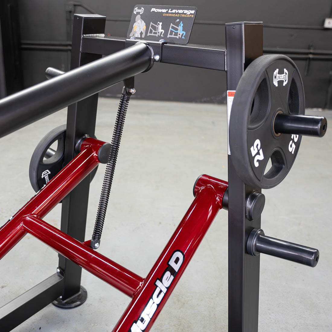 Close-up of a red and black Power Leverage V2 Overhead Triceps machine with a 25lb weight plate.