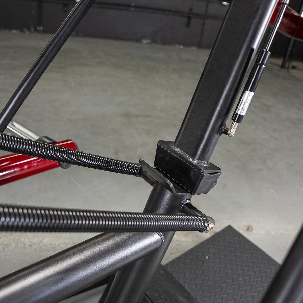 Close-up of the black frame, springs, and hydraulic cylinder of the Power Leverage V2 Pendulum Squat machine.