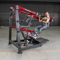 Thumbnail for Woman performing a pendulum squat on a red and black Muscle D Fitness machine with weight plates.