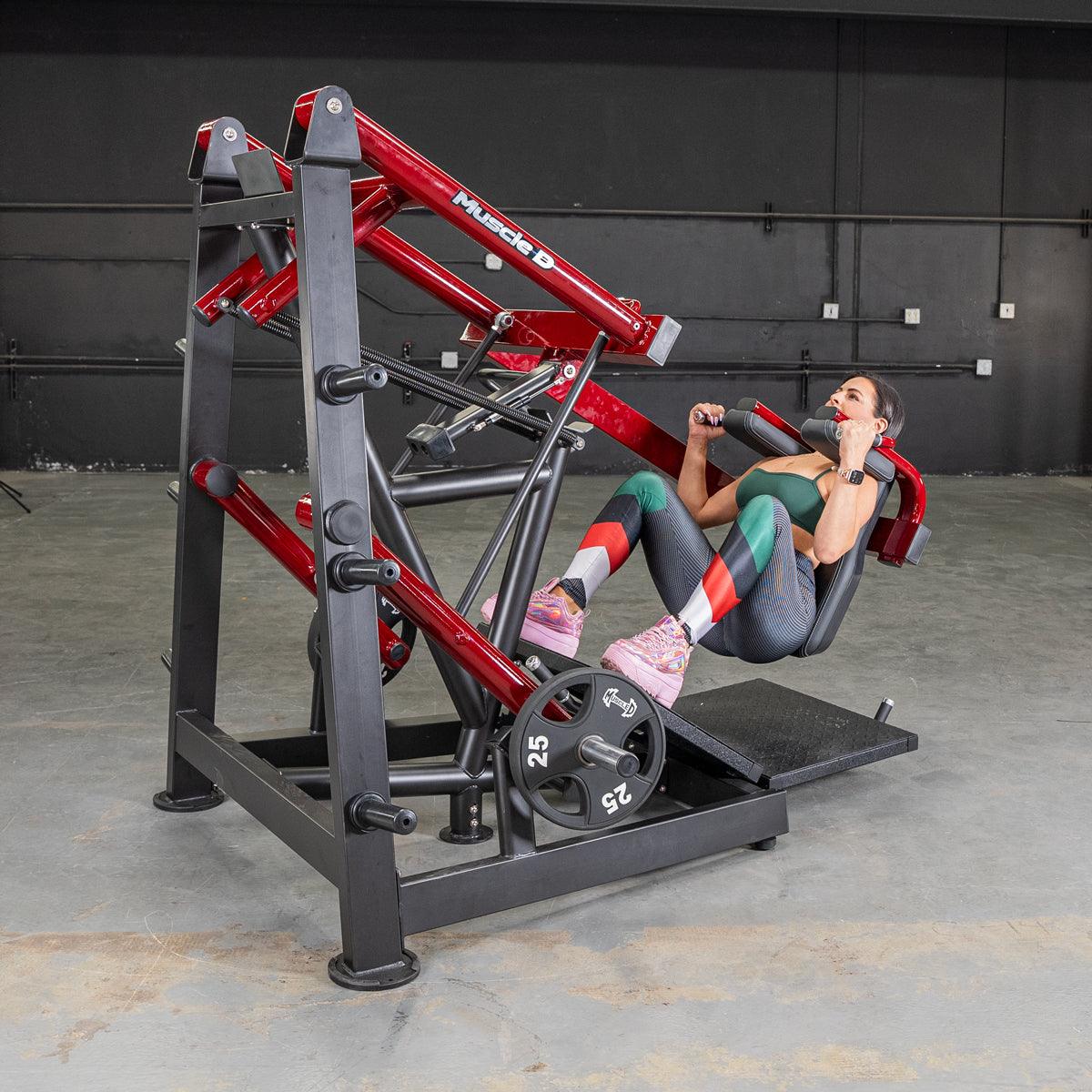 Woman performing squats on a red and black Power Leverage V2 Pendulum Squat machine with a 25lb weight plate.