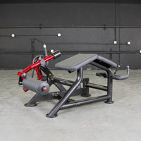 Thumbnail for Black and red prone leg curl machine with a padded bench and rollers in a gym setting.