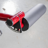 Thumbnail for Close-up of a red leg curl machine's gray padded roller and numbered adjustment plate.