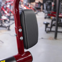 Thumbnail for Close-up of a black padded seat with white stitching on a red metal frame, part of a gym machine.