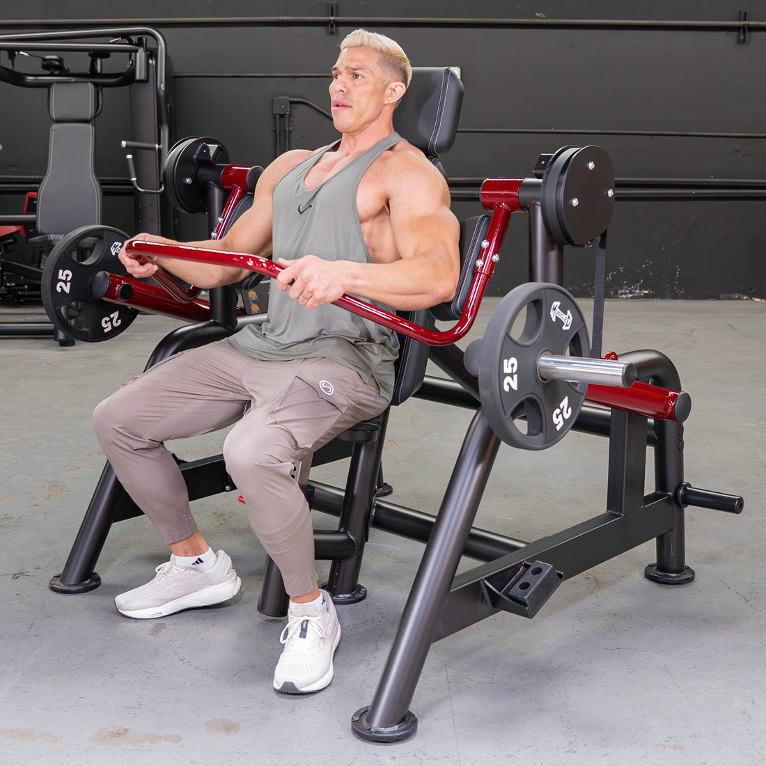 Man in a gym using a red and black Power Leverage V2 Pullover machine with 25lb weights.