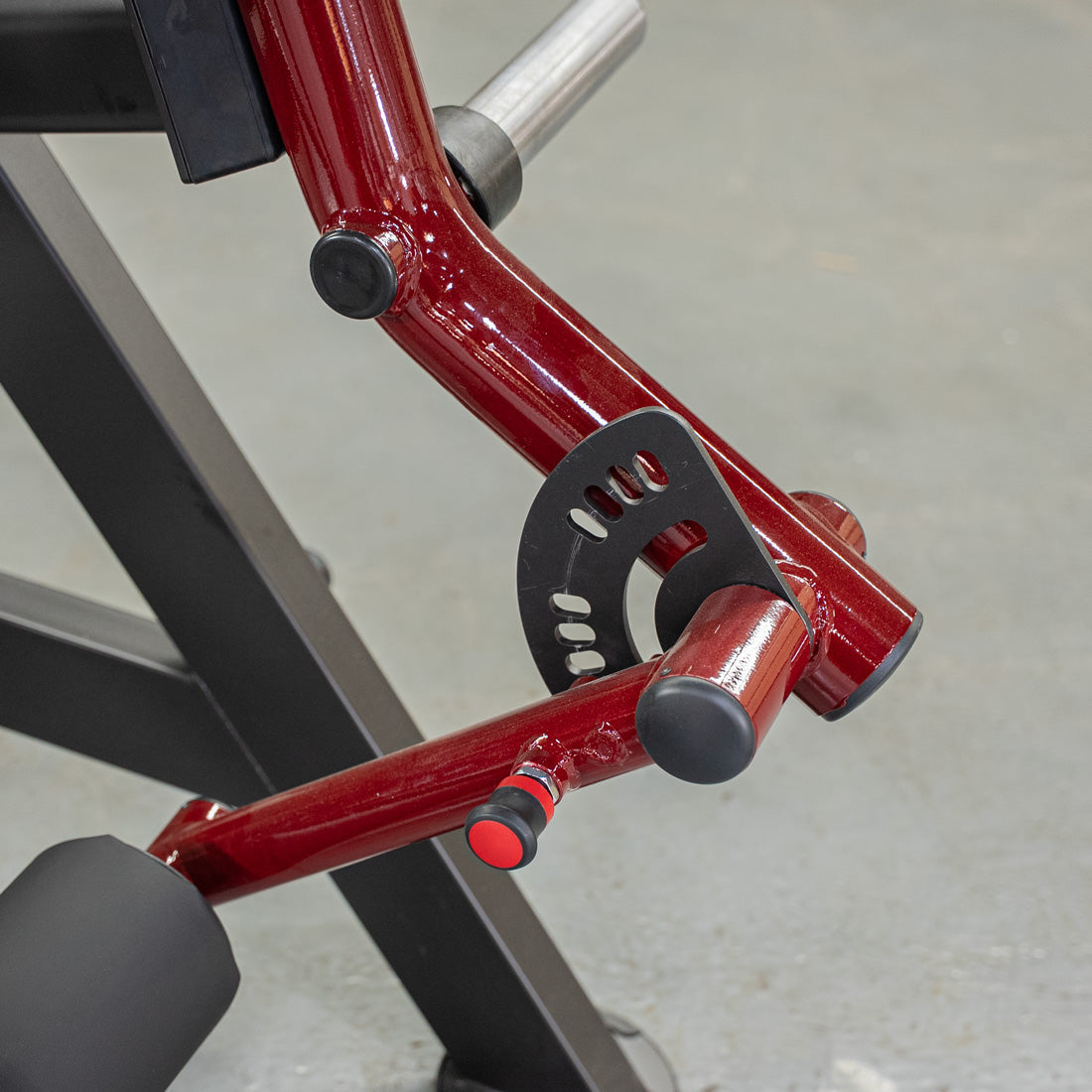 Close-up of a red and black reverse hyper machine, showing the adjustment mechanism and a black padded roller.