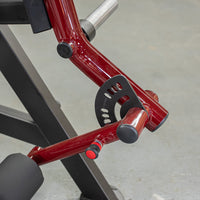 Thumbnail for Close-up of a red and black reverse hyper machine, showing the adjustment mechanism and a black padded roller.