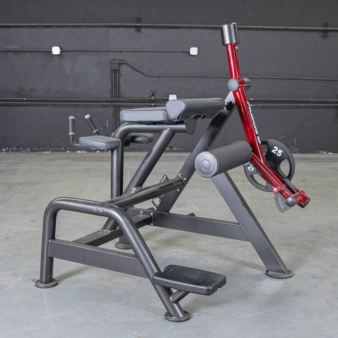 Black and red reverse hyper machine with padded supports, footrests, and a 25lb weight plate.
