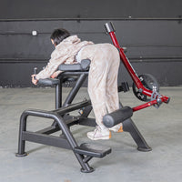 Thumbnail for Person using a red and black reverse hyper machine with a 25lb weight plate.