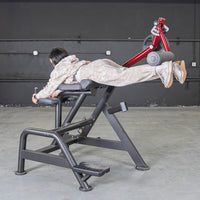 Thumbnail for Person using a black and red reverse hyper machine, lying face down with legs extended.