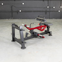 Thumbnail for Red and black seated calf/tib machine with padded seat and leg rests on a concrete floor.
