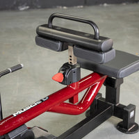 Thumbnail for Close-up of a seated calf/tib machine with red frame, black seat, and adjustable knee pads.