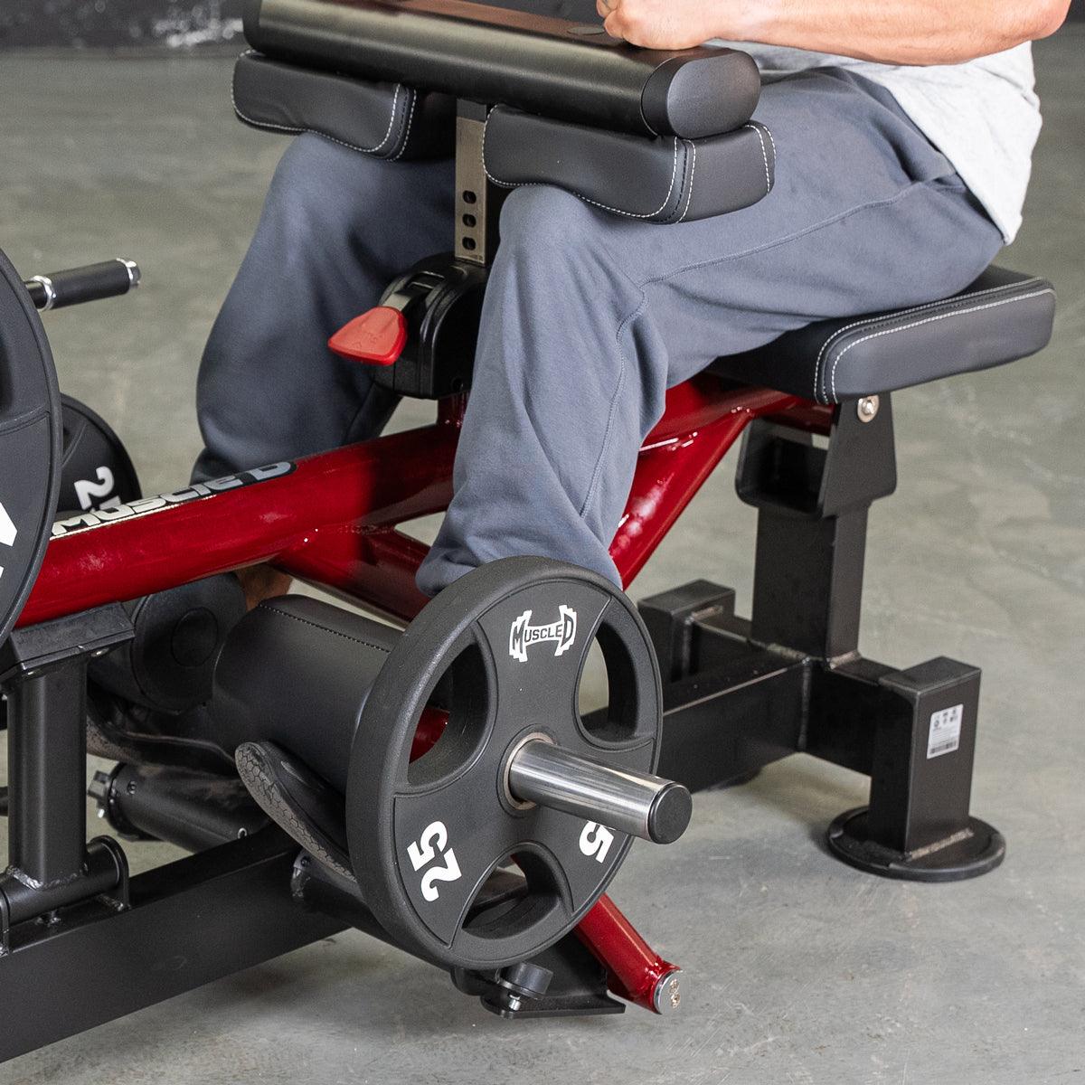 Person using a red and black seated calf and tib machine with a 25lb weight plate.