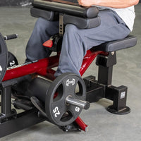 Thumbnail for Person using a red and black seated calf and tib machine with a 25lb weight plate.