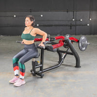 Thumbnail for Woman in green top and patterned leggings using a black and red seated dip/triceps press machine.