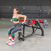Thumbnail for Woman in green sports bra and patterned leggings using a seated dip/triceps press machine.
