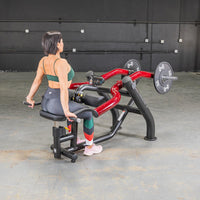 Thumbnail for Woman seated on a black and red dip/triceps press machine with weight plates in a gym.