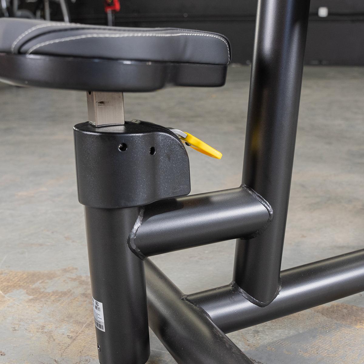 Close-up of the black padded seat and adjustment lever on a seated dip/triceps press machine.