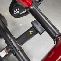 Thumbnail for Close-up of the black and red frame of a seated dip/triceps press machine with a 45lb weight plate.