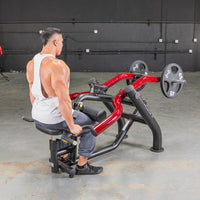 Thumbnail for Man in white tank top using a red and black seated dip/triceps press machine with weight plates.
