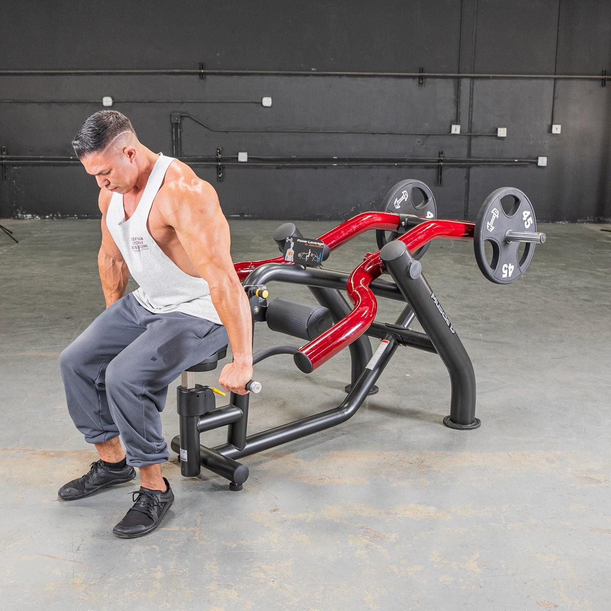 Man using a black and red seated dip/triceps press machine with weight plates in a gym.
