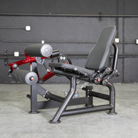 Thumbnail for Black and red seated leg curl machine with a black padded seat and rollers.