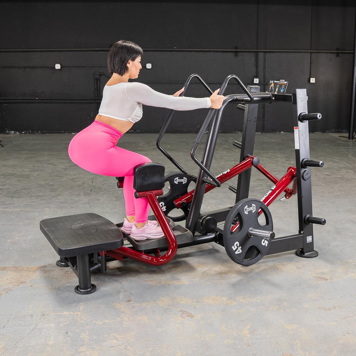 Woman using a red and black standing abductor machine in a gym.