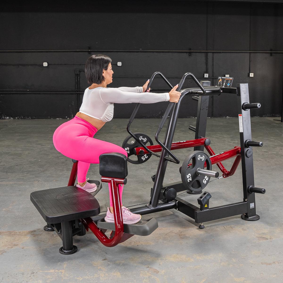 Woman in pink leggings using a red and black standing abductor machine in a gym.