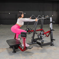 Thumbnail for Woman in pink leggings using a red and black standing abductor machine in a gym.