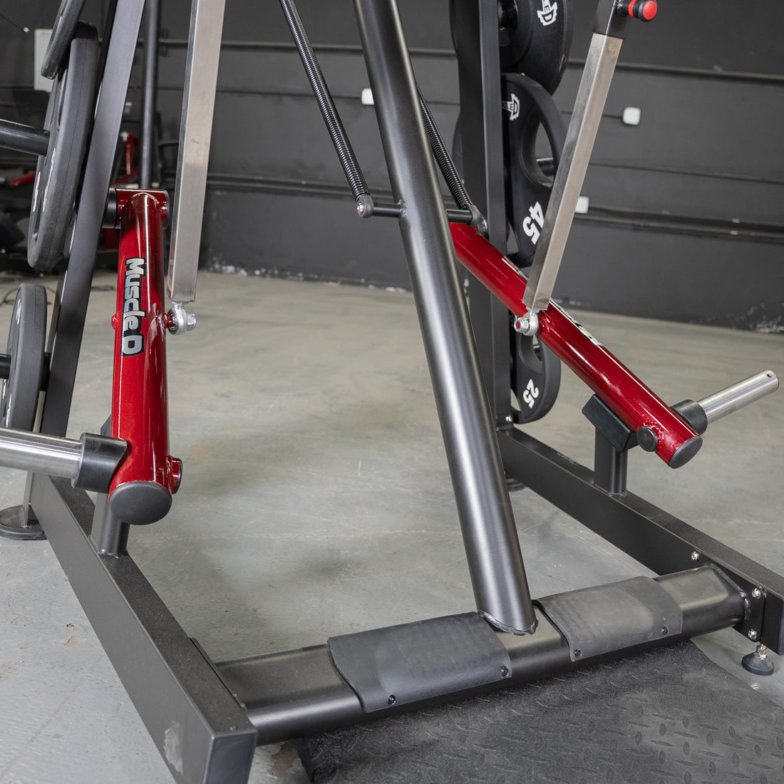 Close-up of the base and red leverage arms of a Viking press machine with weight plates.