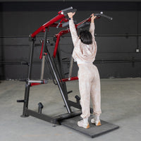 Thumbnail for Woman using a red and black Viking press machine, standing on a black platform with arms extended overhead.