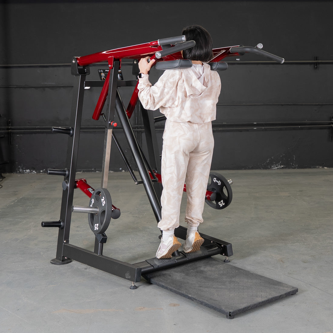 Woman using a red and black Viking press / calf raise machine with weight plates.