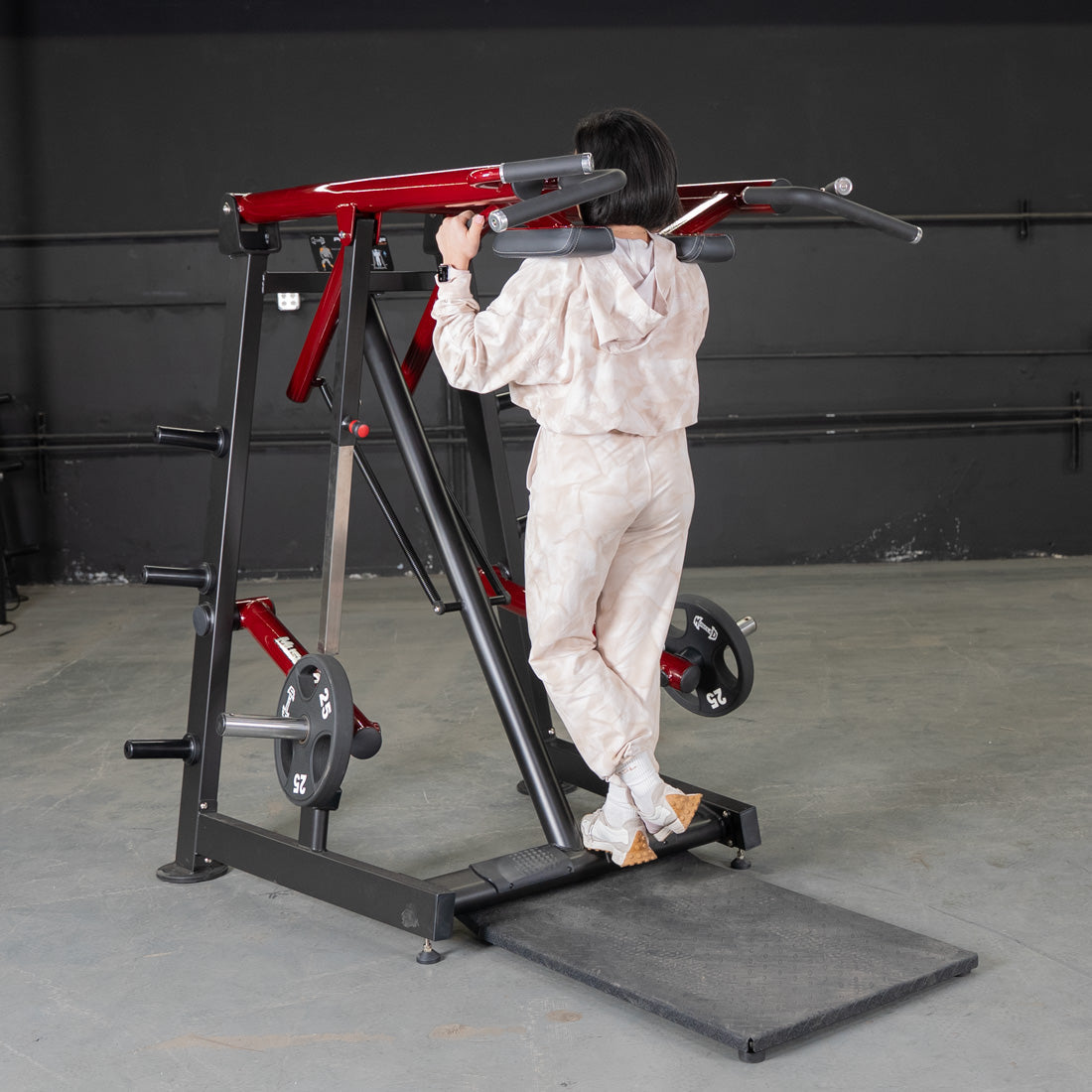 Person using a red and black Viking press machine with weight plates.
