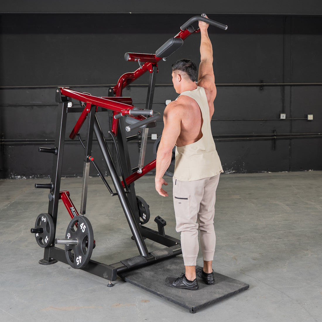 Man using a red and black Viking press machine with weight plates in a gym.