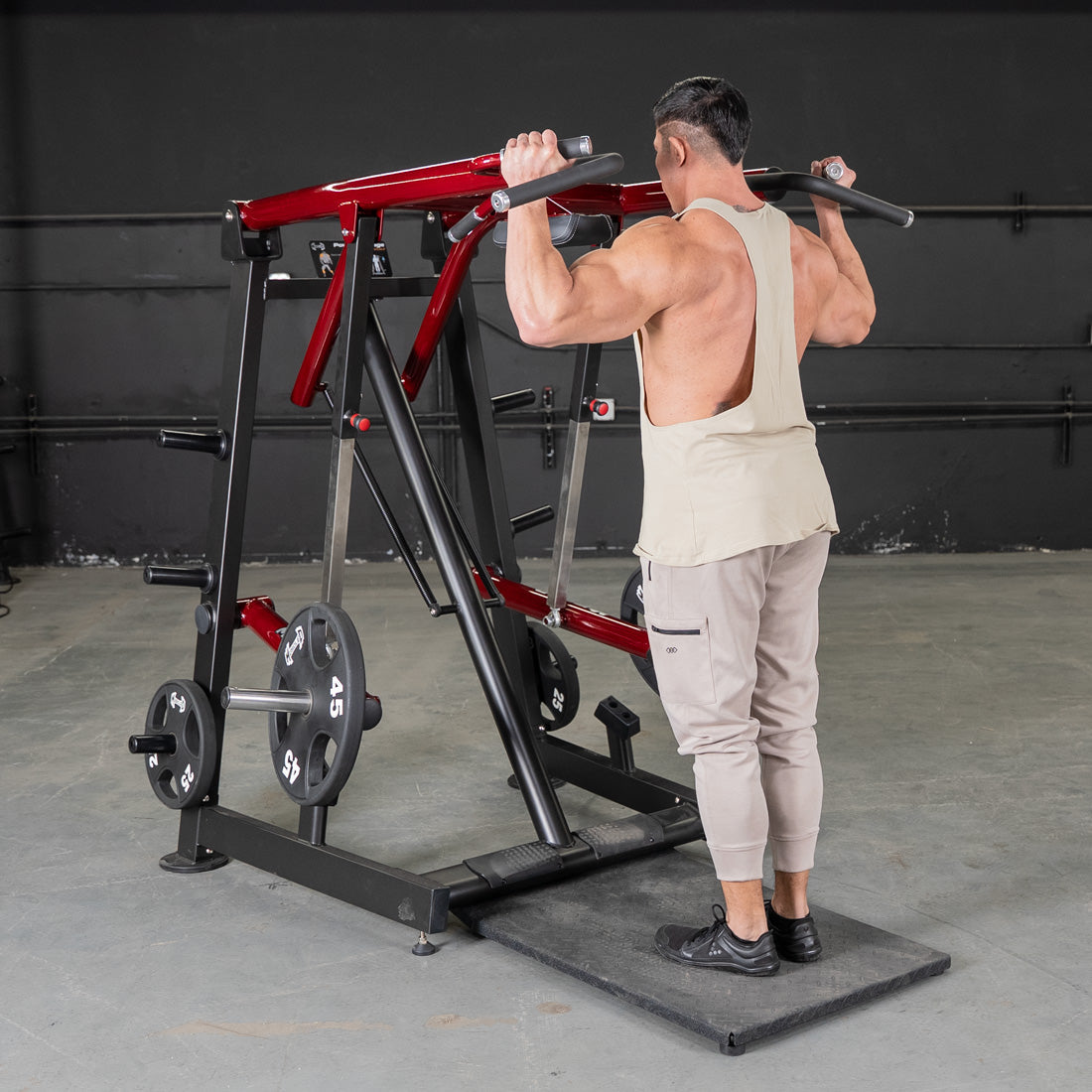 Man using a red and black Viking press machine for a shoulder exercise.